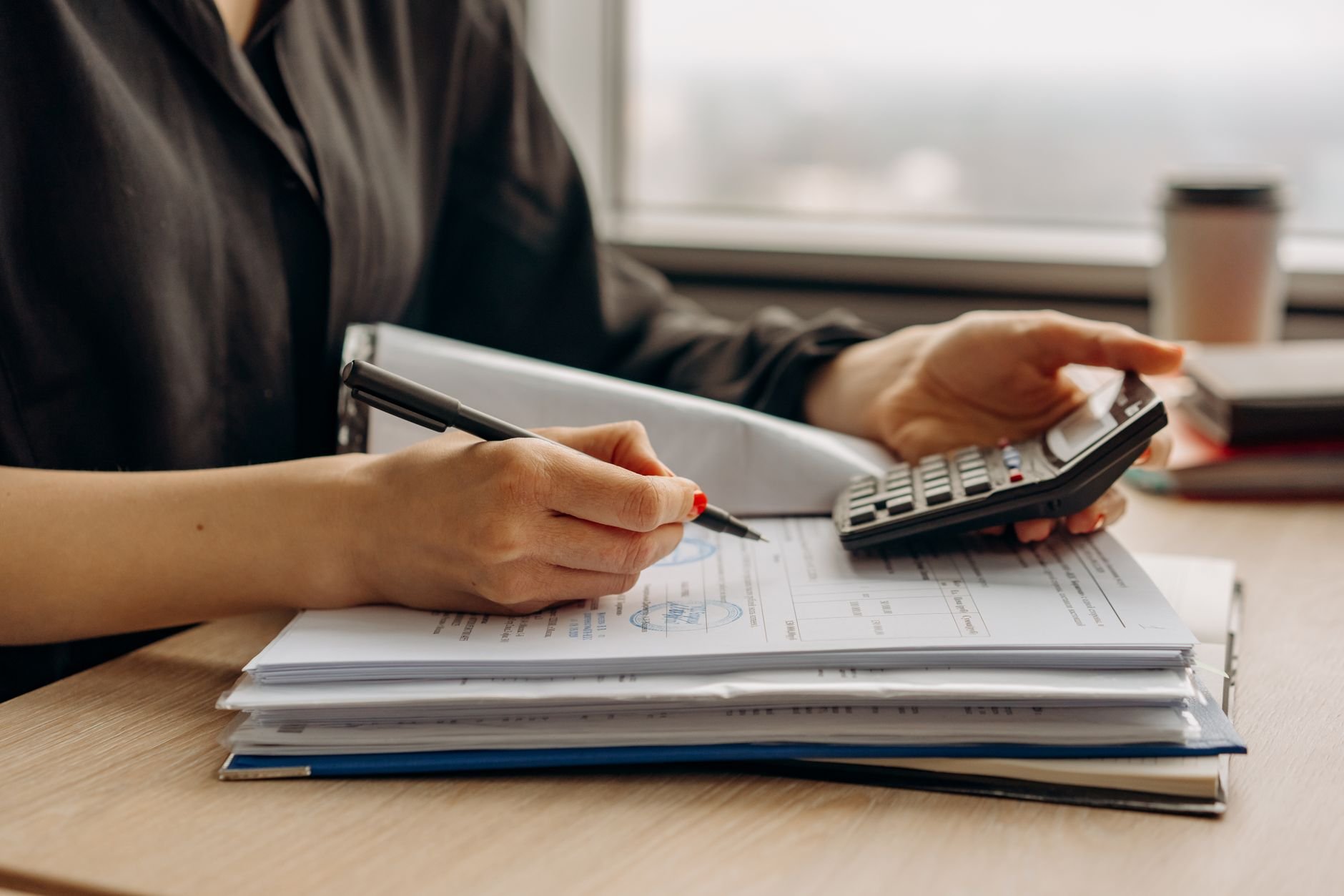 Person reviewing financial documents and invoices with a calculator